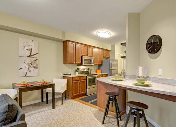 A kitchen with a table and chairs in front of it.