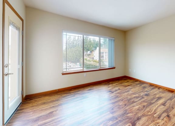a bedroom with hardwood floors and a large window