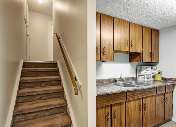 Carpeted stairs lead to an upper floor beside a small kitchen with wood cabinets and a marble countertop here at Lakewood Heights Apartment Homes. The tones are warm and cozy.