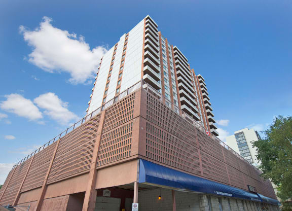 Tall Marquis Towers Apartment Homes residential building against a clear blue sky, featuring brick and glass façade with balconies. A modern, urban atmosphere is conveyed.