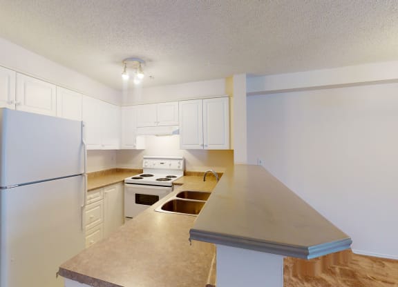 Bright kitchen here at The Pointe at Applewood with white cabinets, stainless steel fridge, electric stove, and dual sink. Beige countertops contrast with light wood flooring. Cozy and inviting.