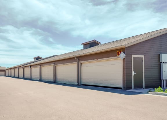 Row of beige garages here at Dakota Ridge Apartment Homes in a clean, empty lot under a clear blue sky. The scene is calm and orderly, with a modern, suburban feel.