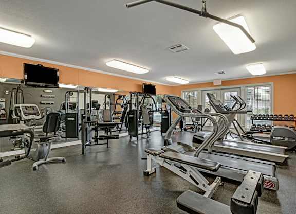 A gym with a variety of equipment including treadmills, weights, and exercise machines.