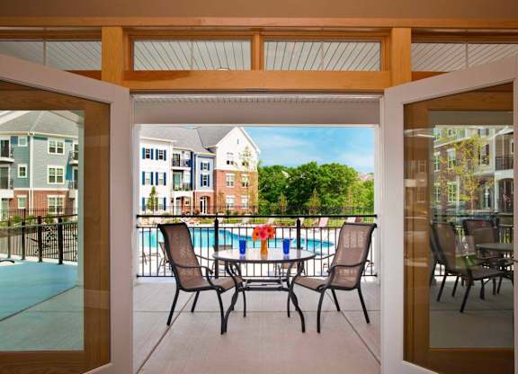 A patio with chairs and a table is shown through a sliding glass door.
