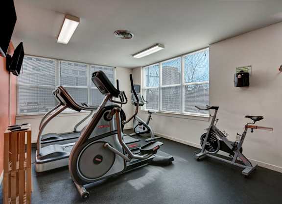 A bright fitness center here at Latitude featuring large corner windows, modern cardio equipment, and a clean, open layout, creating an energizing and welcoming workout space.