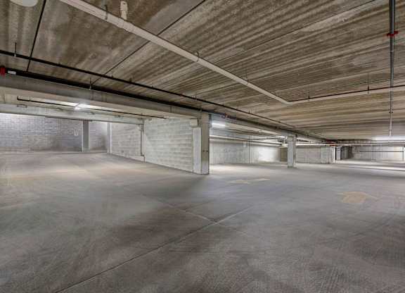 A spacious underground parking garage here at Latitude featuring wide concrete drive lanes, sturdy support columns, and bright overhead lighting, creating a convenient and secure area for resident parking.