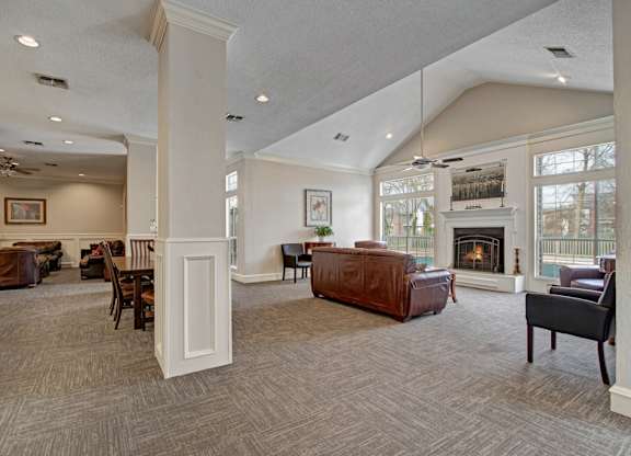 A spacious resident lounge here at St. James Place with comfortable seating, high ceilings, and large windows that bring in natural light. A cozy fireplace and open layout create a warm and inviting gathering space.
