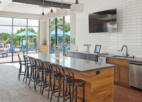 A kitchen with a long counter and bar stools.