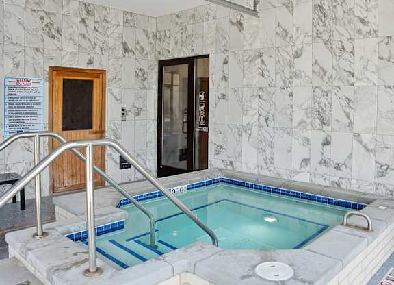 A small indoor pool with a marble wall.