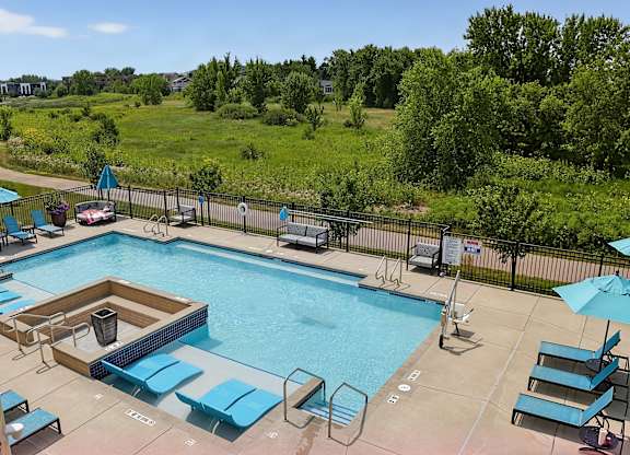 A large outdoor swimming pool surrounded by blue lounge chairs and umbrellas.
