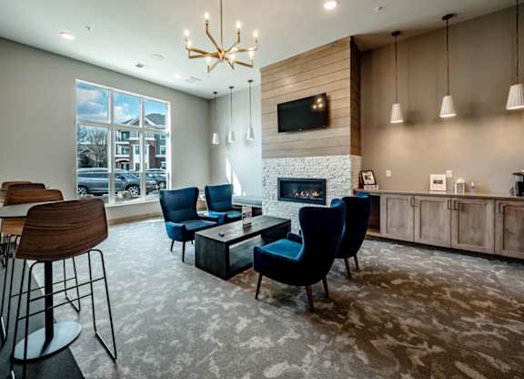 A welcoming resident lounge here at Van Buren East with blue accent chairs, a modern fireplace, and large bright windows. Sleek lighting, warm finishes, and comfortable seating create a stylish and inviting gathering space.