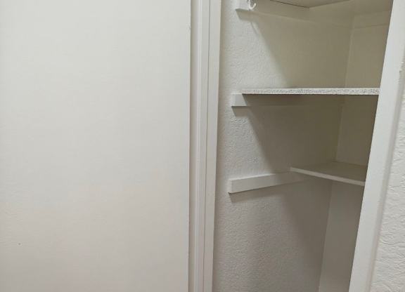 A white closet with shelves and a door open.