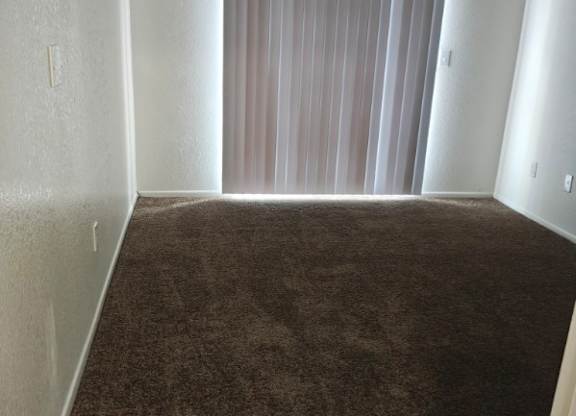 A long hallway with carpeted floors and white walls.