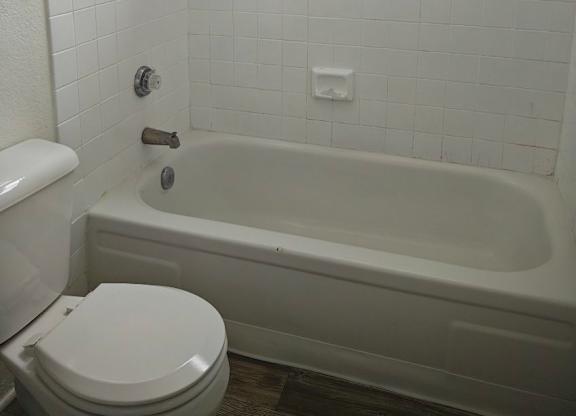 A white toilet sits next to a white bathtub in a bathroom.