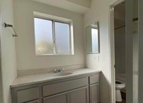 A bathroom with a window, sink, and wooden floors.