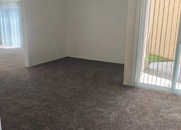 A room with a carpeted floor and a sliding glass door.