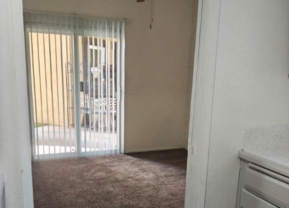 A room with a ceiling fan and a window with blinds.