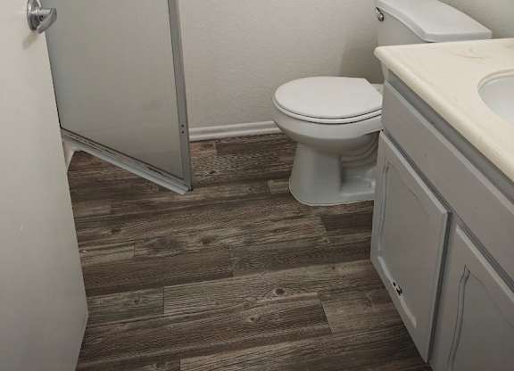 A white toilet sits in a bathroom next to a sink.