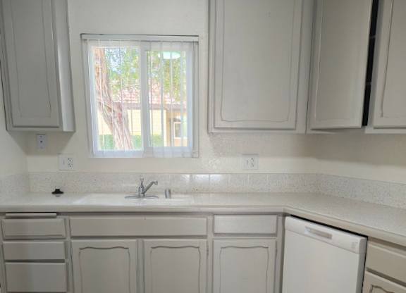 A kitchen with white cabinets and a wooden floor.