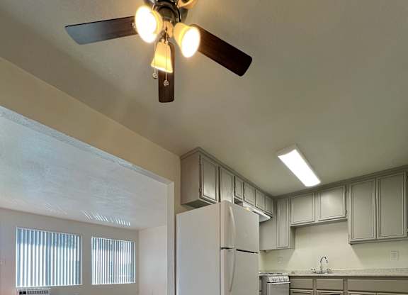 A kitchen with a white fridge and wooden floors.