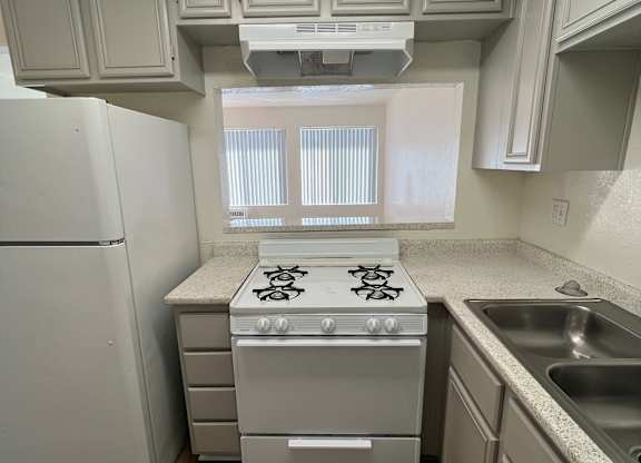 A kitchen with a white refrigerator, a white stove, and a white oven.