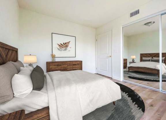 A bedroom with a large bed and a mirror on the wall.