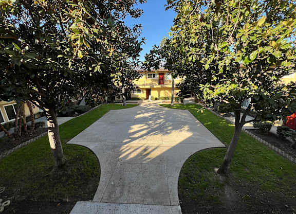A pathway between two trees with a building in the background.