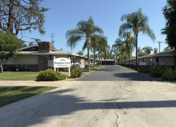 A street view of a residential area with houses and palm trees.