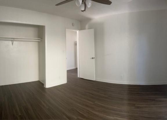 A room with a ceiling fan and two open doors.