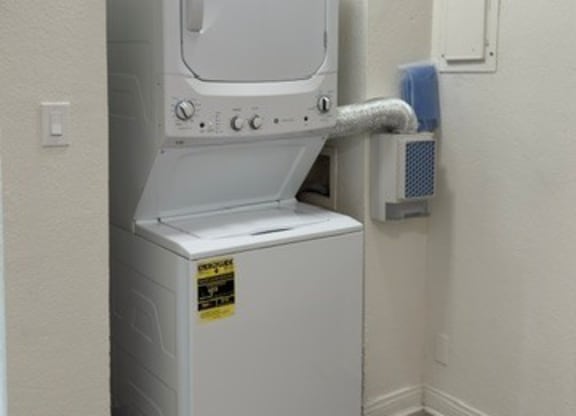 A small white refrigerator with a door missing is in a room.