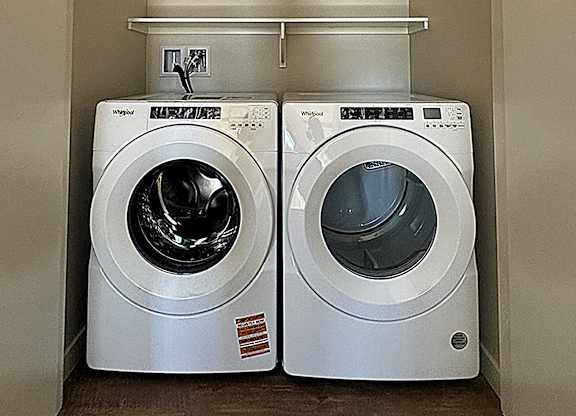 Two front loading washing machines in a small laundry room.