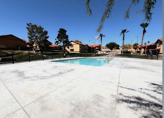 A pool surrounded by a fence and palm trees.