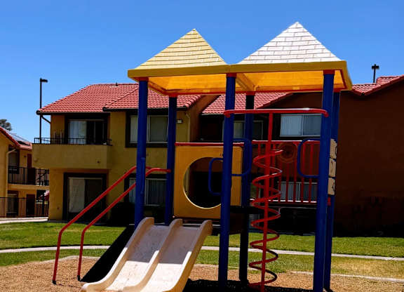 A playground with a yellow slide and a red and blue structure.