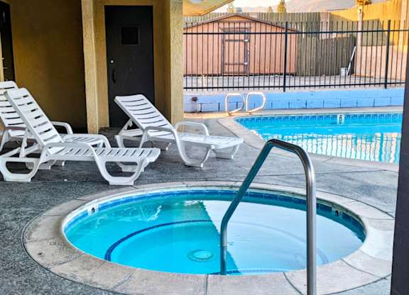 A small round pool with a ladder and two chairs.