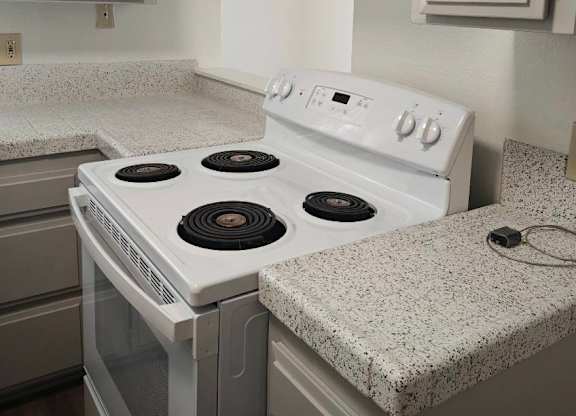 A white stove top oven with four burners is in a kitchen.