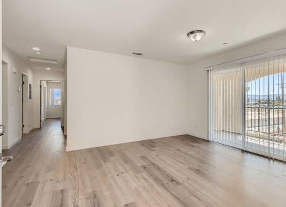 A spacious room with wooden flooring and white walls.