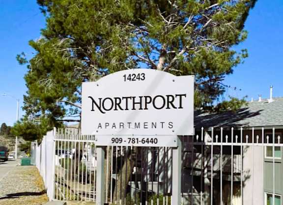 A sign for Northport Apartments is displayed in front of a tree.