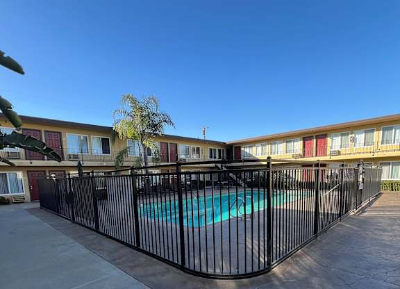 A pool surrounded by a black fence in front of a building.