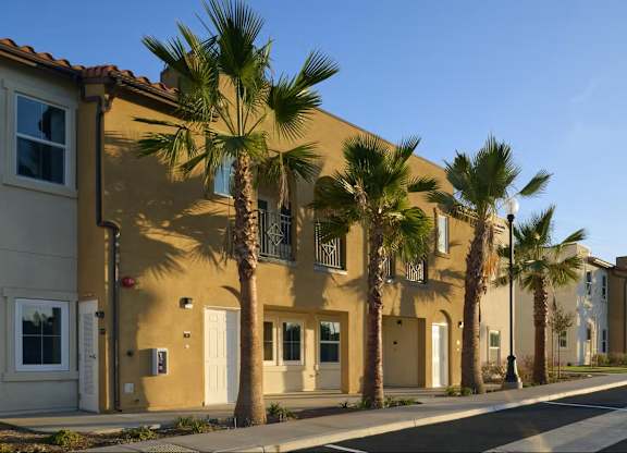 A row of houses with palm trees in front.