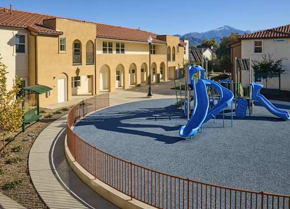 A playground with a blue slide in front of a building.