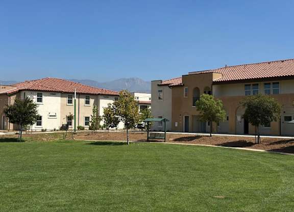 A building with a red tile roof is in the background of a grassy field.