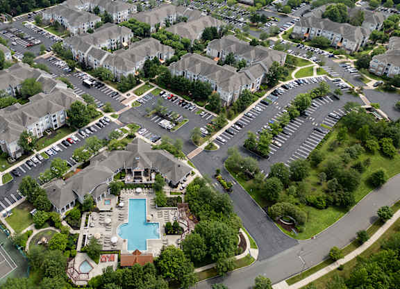 A bird's eye view of a residential complex with a swimming pool and tennis court.