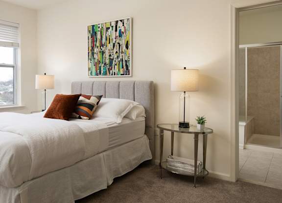 A bedroom with a large bed and a painting on the wall.