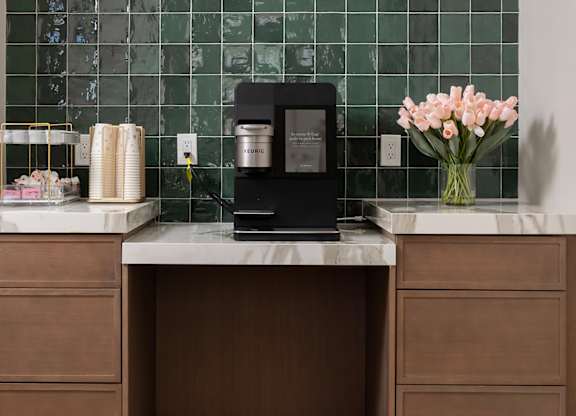 A kitchen counter with a vase of flowers and a coffee maker.