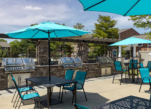 Patio with blue umbrellas and tables with chairs at The Crest at Princeton Meadows, Plainsboro, NJ.