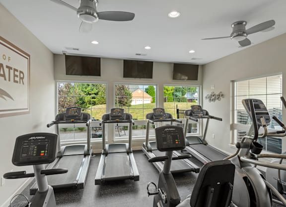 A gym with treadmills and a wall sign that says