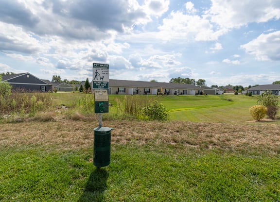 A green sign in a field with a cloudy sky in the background.