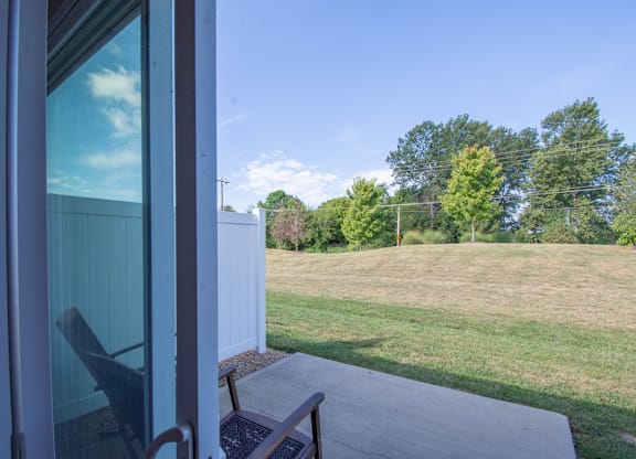 A chair sits on a patio looking out to a green lawn.