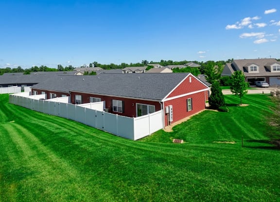 A red and white house with a grey roof is surrounded by a green lawn.