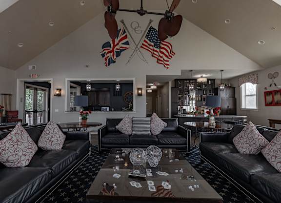 A living room with a black leather couch and a coffee table in the center.